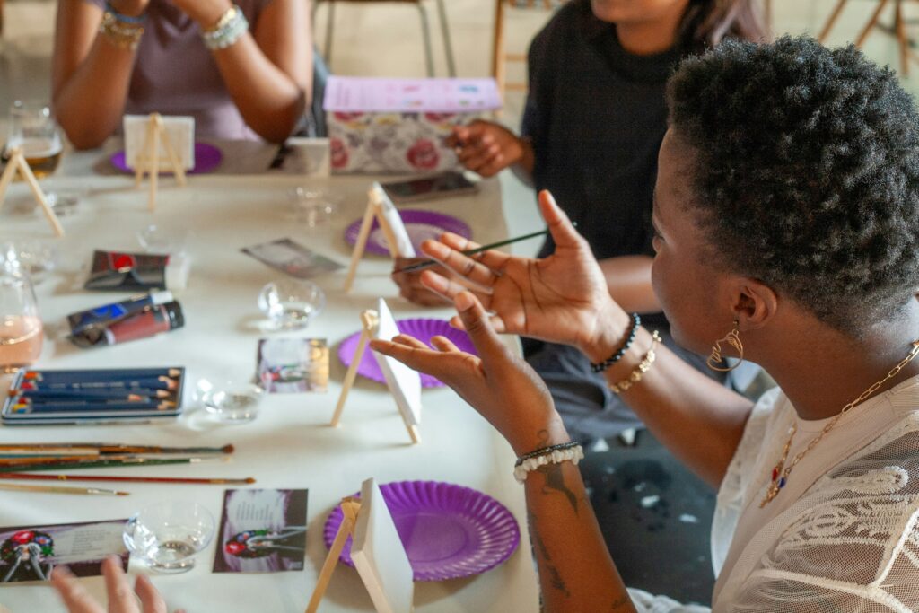 People painting and talking at a table with art supplies
