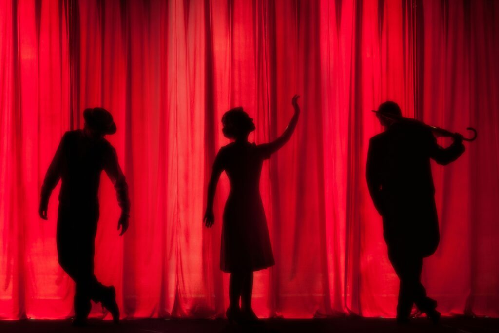 Red stage curtains with shadow outlines of actors